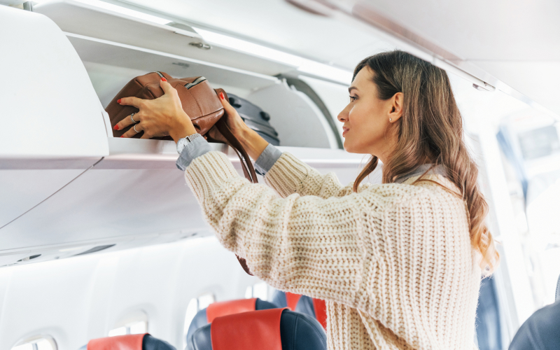 Mujer guardando bolso en un avión